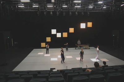 View of a dance stage in a theater, with three dancers and three musicians mid-performance.